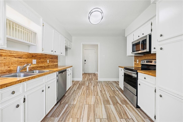 kitchen featuring sink, stainless steel appliances, light hardwood / wood-style floors, white cabinets, and decorative backsplash