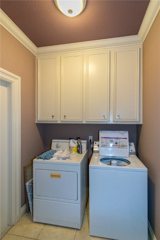 washroom with crown molding, a textured ceiling, light tile patterned floors, cabinets, and washer and dryer