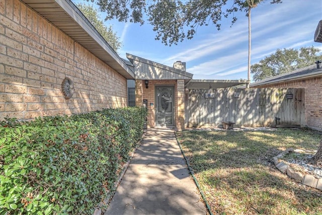 view of exterior entry featuring a lawn