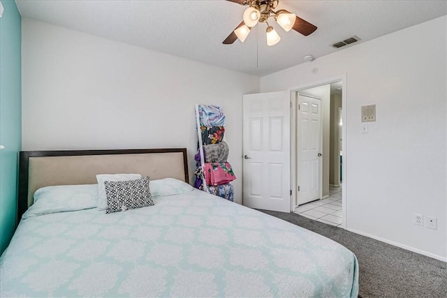 bedroom with ceiling fan, light colored carpet, and a textured ceiling