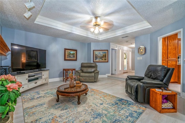 living room featuring a raised ceiling, visible vents, a textured ceiling, and wood finished floors