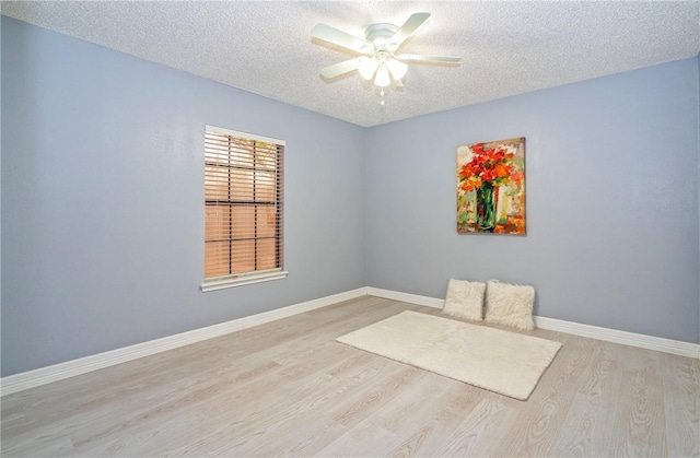 unfurnished room with ceiling fan, a textured ceiling, baseboards, and wood finished floors