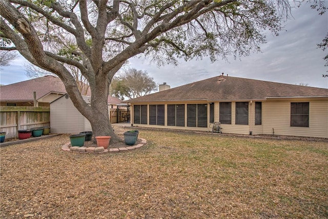 rear view of property featuring a yard, a chimney, fence, and a sunroom