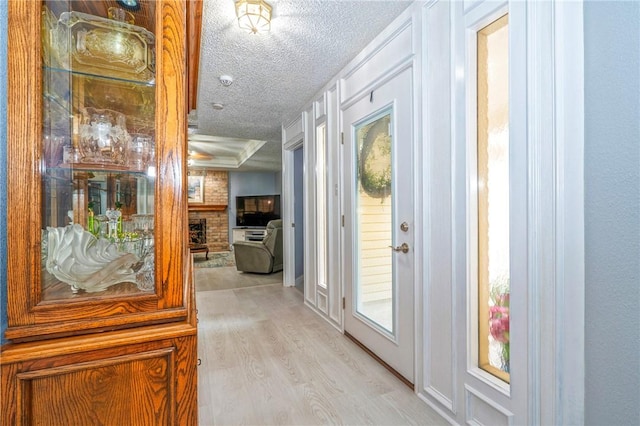 doorway to outside with light wood-style floors, a fireplace, and a textured ceiling