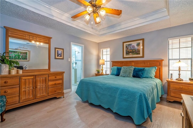 bedroom with a textured ceiling, a tray ceiling, multiple windows, and light wood-type flooring