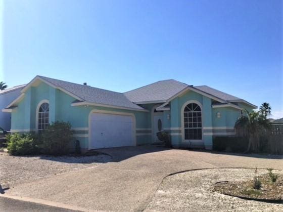 ranch-style home with a garage, driveway, and stucco siding