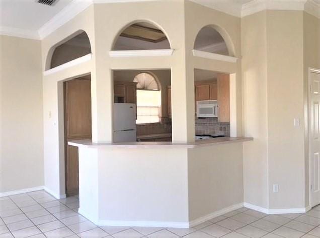 kitchen featuring light tile patterned floors, a peninsula, white appliances, decorative backsplash, and crown molding