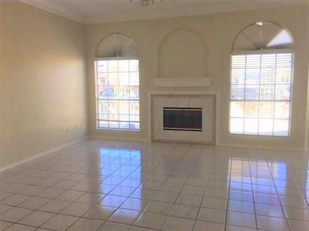 unfurnished living room featuring light tile patterned floors, baseboards, a fireplace, and ornamental molding