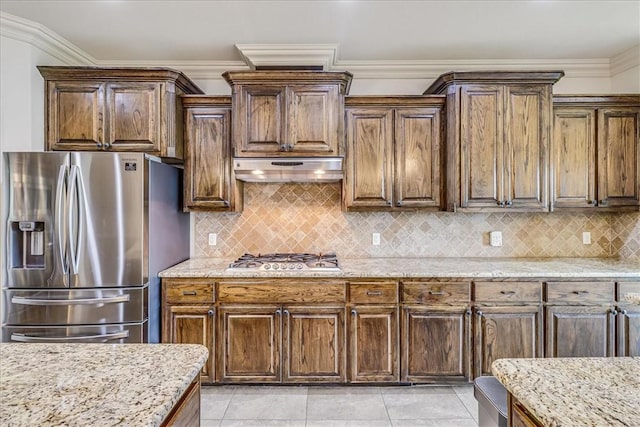 6241 Lago Vista Dr, Corpus Christi, TX 78414 - kitchen featuring appliances with stainless steel finishes, under cabinet range hood, light stone counters, decorative backsplash, and light tile patterned floors