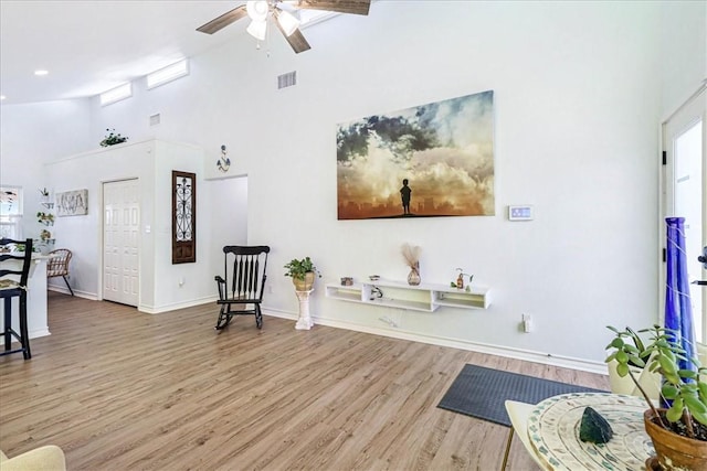 living area with visible vents, high vaulted ceiling, wood finished floors, a healthy amount of sunlight, and ceiling fan