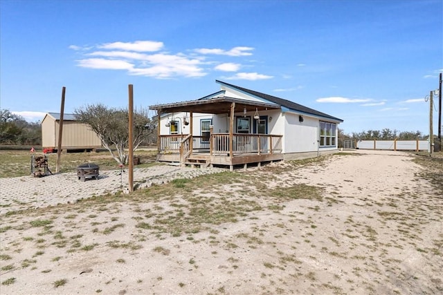 rear view of property with an outbuilding, a wooden deck, a shed, and an outdoor fire pit