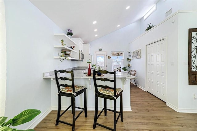 kitchen featuring visible vents, a breakfast bar, open shelves, a peninsula, and light countertops