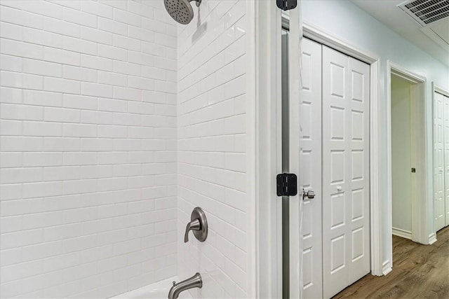 bathroom featuring visible vents,  shower combination, and wood finished floors