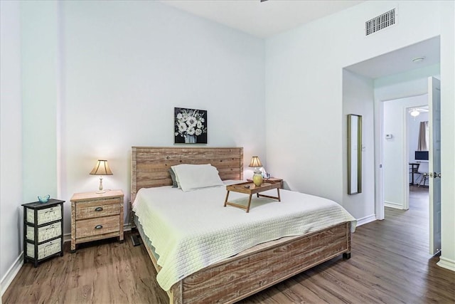 bedroom with visible vents, baseboards, and wood finished floors