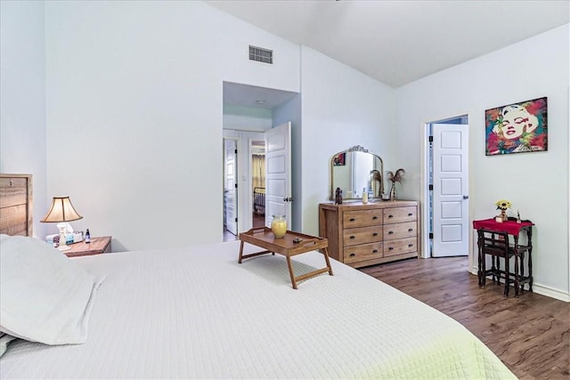 bedroom with vaulted ceiling, visible vents, and wood finished floors