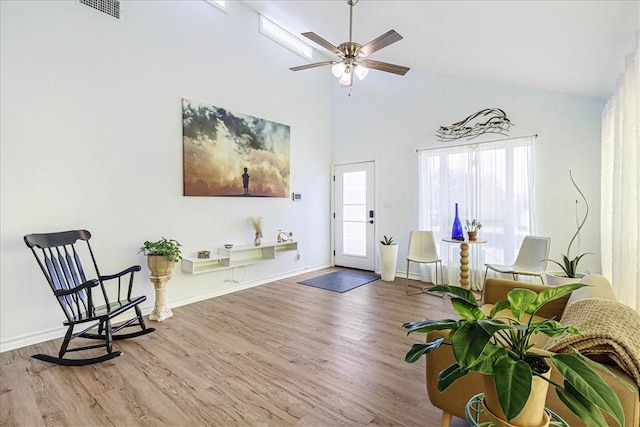 living area with visible vents, high vaulted ceiling, wood finished floors, baseboards, and ceiling fan