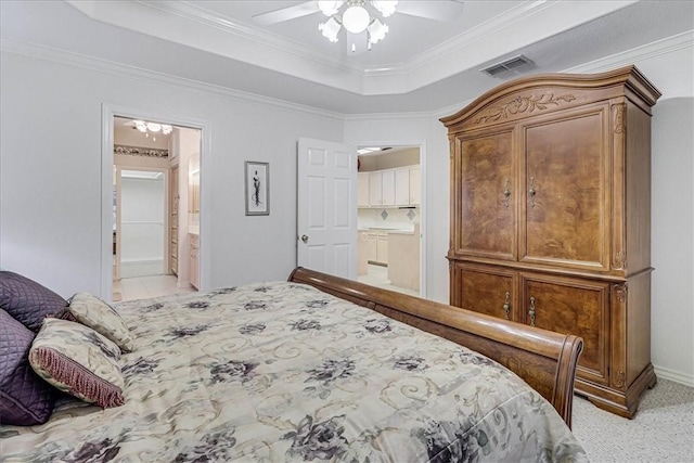 bedroom with connected bathroom, light colored carpet, ceiling fan, a tray ceiling, and crown molding