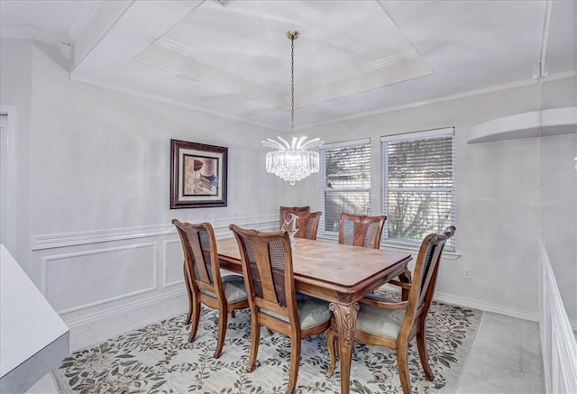 tiled dining space featuring ornamental molding, a tray ceiling, and a chandelier