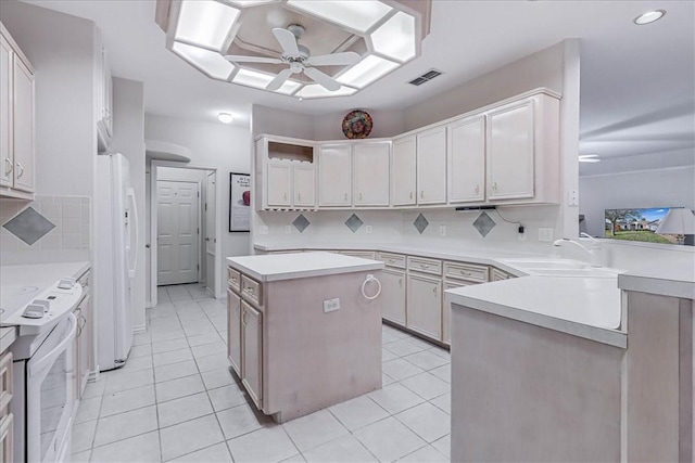 kitchen with sink, white appliances, ceiling fan, a kitchen island, and kitchen peninsula