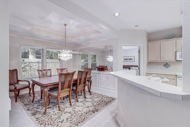 dining area featuring a raised ceiling, light tile patterned flooring, sink, and a notable chandelier