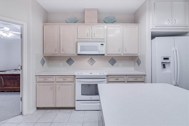 kitchen with tasteful backsplash, light tile patterned floors, and white appliances