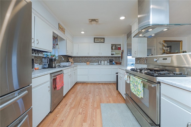 kitchen featuring stainless steel appliances, light hardwood / wood-style floors, island range hood, white cabinets, and sink