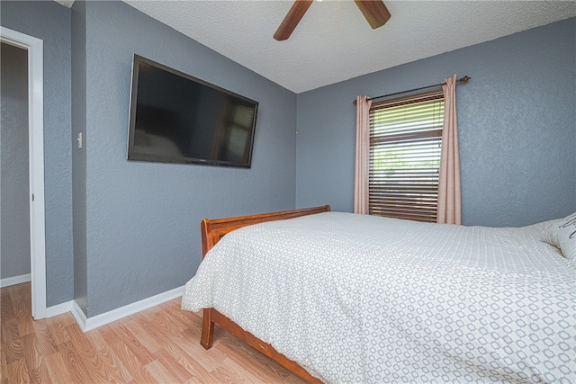 bedroom with hardwood / wood-style floors, ceiling fan, and a textured ceiling