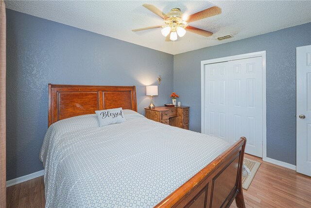 bedroom featuring ceiling fan, wood-type flooring, a textured ceiling, and a closet