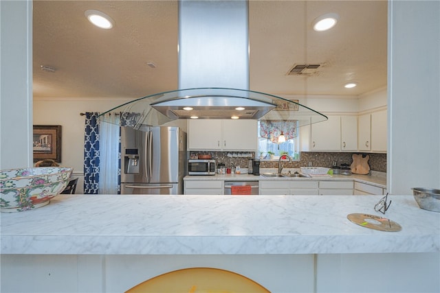 kitchen featuring island range hood, white cabinetry, sink, and appliances with stainless steel finishes