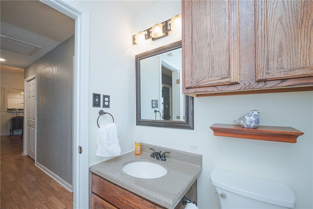 bathroom with wood-type flooring, vanity, toilet, and a textured ceiling