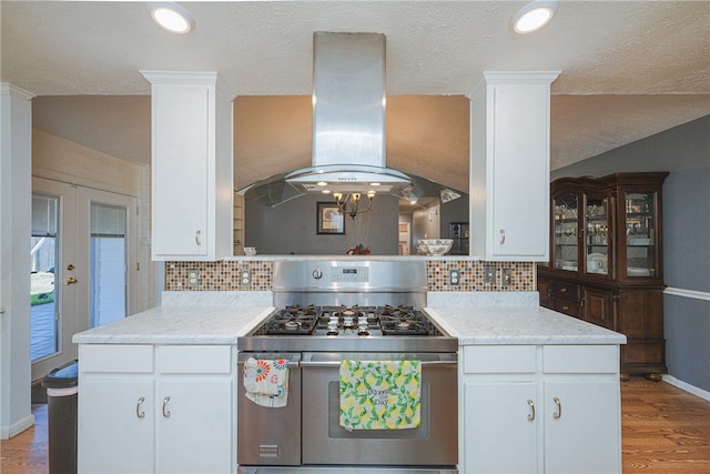 kitchen featuring high end range, light wood-type flooring, extractor fan, and white cabinetry