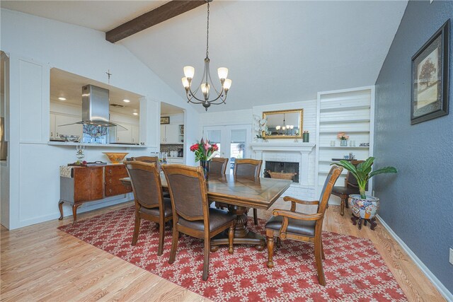 dining space featuring lofted ceiling with beams, a chandelier, light hardwood / wood-style floors, and a fireplace