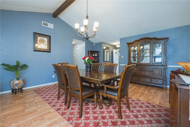 dining area with lofted ceiling with beams, light hardwood / wood-style floors, and an inviting chandelier