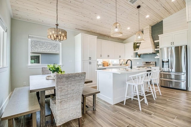 1911 Eskridge Rd, Port Aransas, TX 78373 - kitchen featuring appliances with stainless steel finishes, wood ceiling, custom range hood, light countertops, and a chandelier