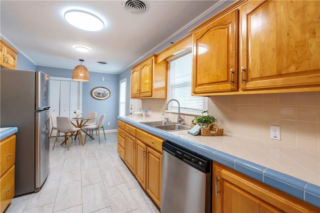 253 Melrose, Corpus Christi, TX 78404 - kitchen featuring appliances with stainless steel finishes, a sink, backsplash, brown cabinets, and decorative light fixtures