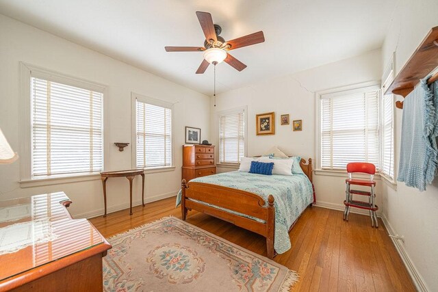 bedroom with multiple windows, ceiling fan, light wood-style flooring, and baseboards