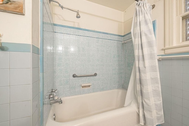 full bath with tile walls and shower / bathtub combination with curtain