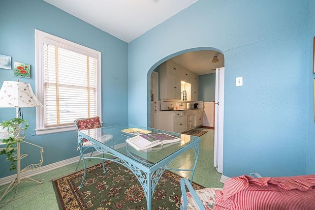 dining space with arched walkways, baseboards, and tile patterned floors