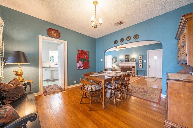 dining room with arched walkways, a wealth of natural light, visible vents, and light wood-style floors
