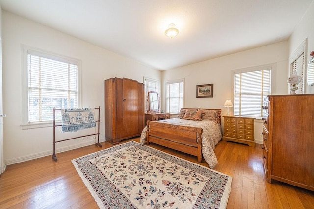 bedroom featuring multiple windows, light wood-style flooring, and baseboards