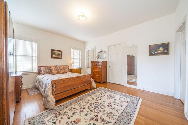bedroom with baseboards, multiple windows, and light wood-style floors