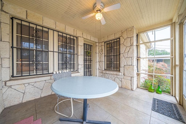 sunroom / solarium with a ceiling fan and wooden ceiling