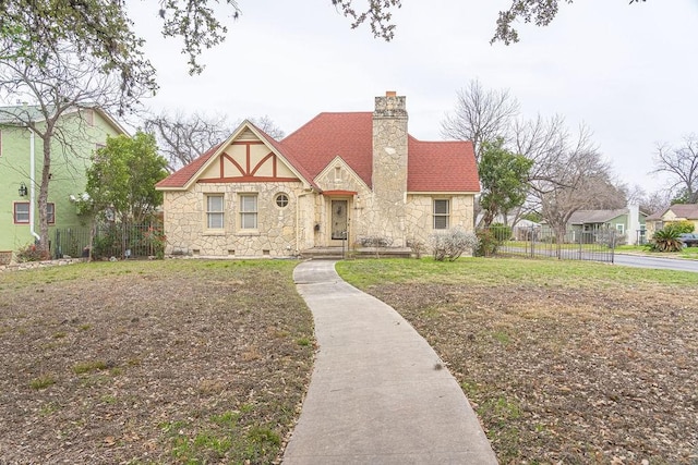 english style home with stone siding, crawl space, a chimney, and fence