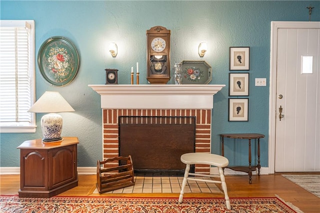 interior space with a brick fireplace, baseboards, and wood finished floors