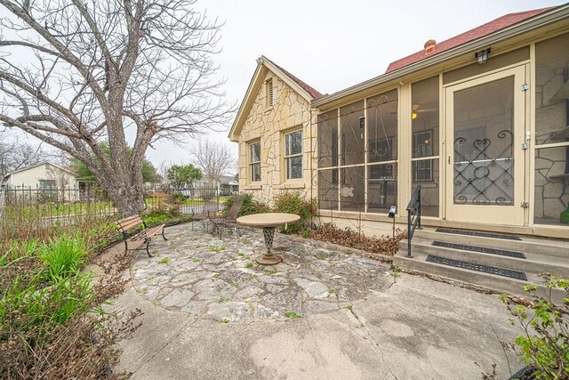 view of patio / terrace with entry steps, a sunroom, and fence