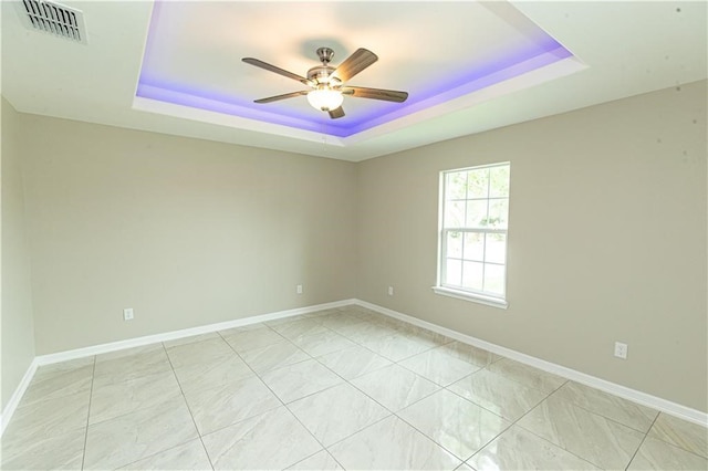 empty room featuring a tray ceiling and ceiling fan