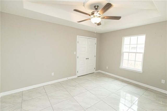 spare room with ceiling fan and a raised ceiling