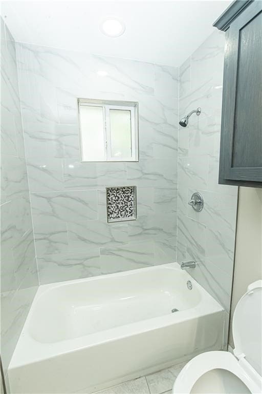 bathroom featuring toilet and tiled shower / bath