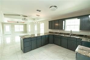 kitchen with kitchen peninsula, sink, light tile patterned floors, and dark stone counters