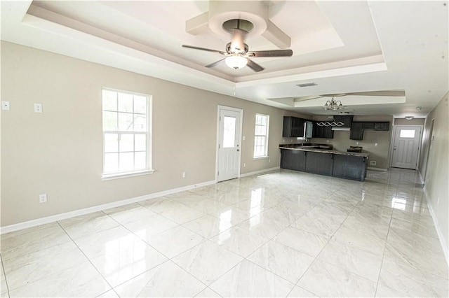 unfurnished living room featuring ceiling fan and a tray ceiling